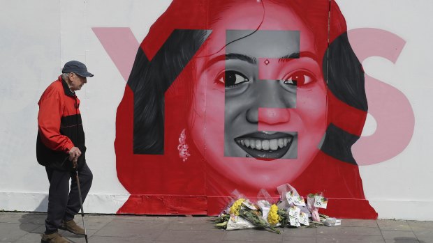 A man walks past a mural showing Savita Halappanavar, a 31-year-old Indian dentist who had sought and been denied an abortion before she died after a miscarriage in a Galway hospital.
