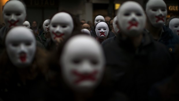 People wear white masks in support of Catalonian politicians jailed on charges of sedition and condemning the arrest of Catalonia's former president, Carles Puigdemont, in Germany.