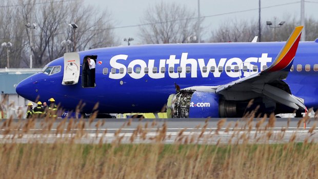 The Southwest Airlines plane sits on the runway with a damaged engine on the left side.
