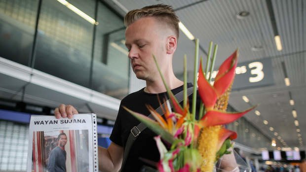 Dutchman Arthur Laumann holds a floral tribute and photograph of family friend Wayan Sujana of Bali, believed to be missing on Malaysia Airlines flight MH17 at Schiphol Airport in Amsterdam, Netherlands. Malaysia Airlines flight MH17 was ravelling from Amsterdam to Kuala Lumpur.