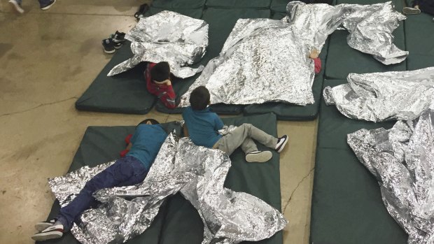 Teens who've been taken into custody on the US-Mexico border rest in one of the cages at a facility in McAllen, Texas.