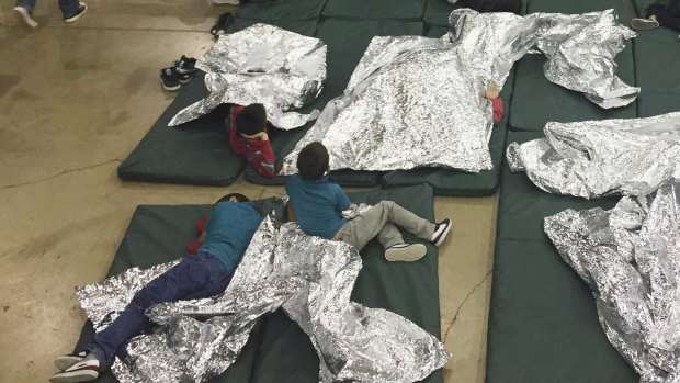 Teens who have been taken into custody on the US-Mexico border rest in one of the cages at a facility in McAllen, Texas.