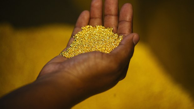 A worker holds a handful of gold bullion granules during manufacture  in South Africa.