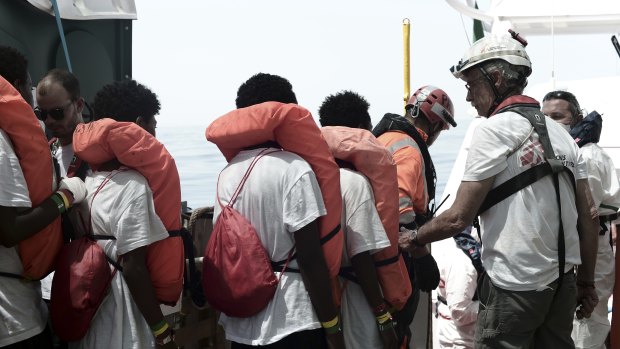 Migrants are transferred from the Aquarius to an Italian coast guard vessel at sea so they can be taken to Spain.