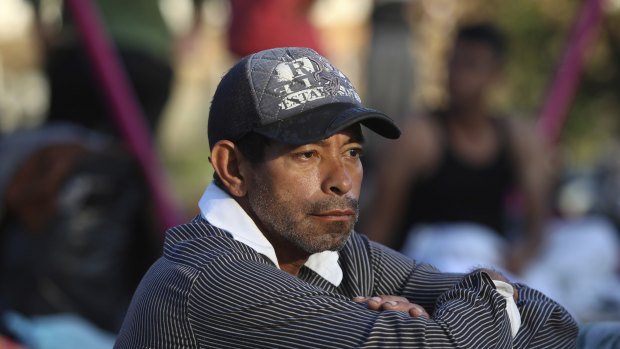 A man sits amidst other sleeping migrants at a sports club where Central American migrants travelling with the annual "Stations of the Cross" caravan are camped out, in Matias Romero, Oaxaca State, Mexico.