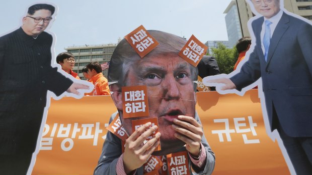 A protester wearing a mask of US President Donald Trump, centre, performs with cut-out photos of North Korean leader Kim Jong-un and South Korean President Moon Jae-in, right, during a rally against the US in Seoul on Friday.