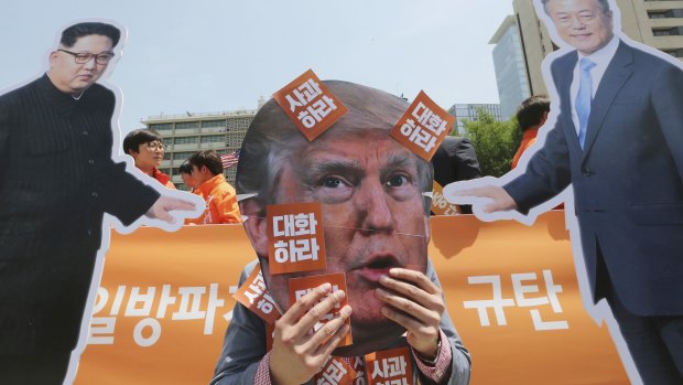 A protester wearing a mask of US President Donald Trump, centre, performs with cut-out photos of North Korean leader Kim Jong-un and South Korean President Moon Jae-in, right, during a rally against the US in Seoul on Friday.