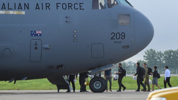 The Australian Federal Police dive team and support staff walk over the tarmac at Chiang Rai airport to board an Australian RAAF plane bound for Canberra.