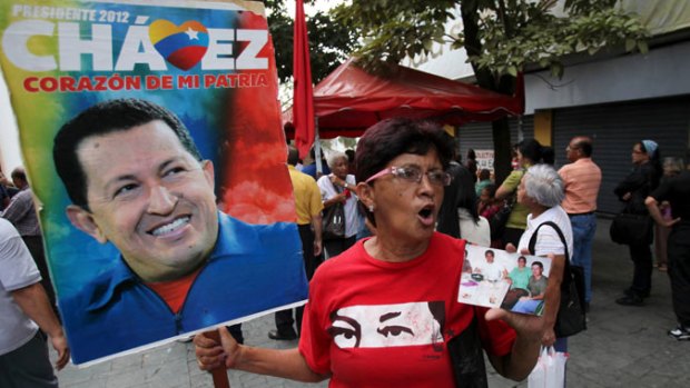 A supporter of Venezuela's President Hugo Chavez holds photos of Chavez in Bolivar square in Caracas, Venezuela.