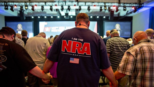 Members of the National Rifle Association (NRA) hold hands during an opening prayer at the NRA annual meeting in Dallas, Texas