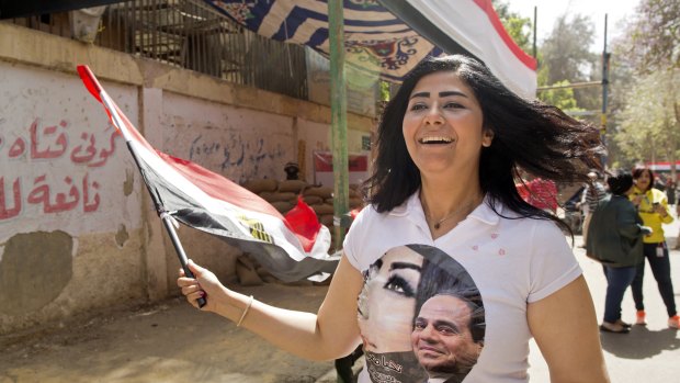 A Sisi supporter wears a T-shirt with his picture as she chants national songs in front of a polling station in Cairo on Monday.