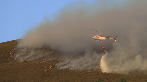 A helicopter drops water as firefighters tackle the wildfire on Saddleworth Moor, England, on Wednesday.