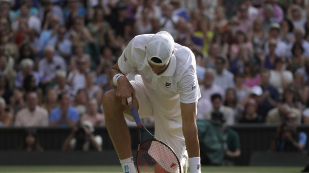 An exhausted Isner kneels after stumbling as he returned the ball to Anderson.