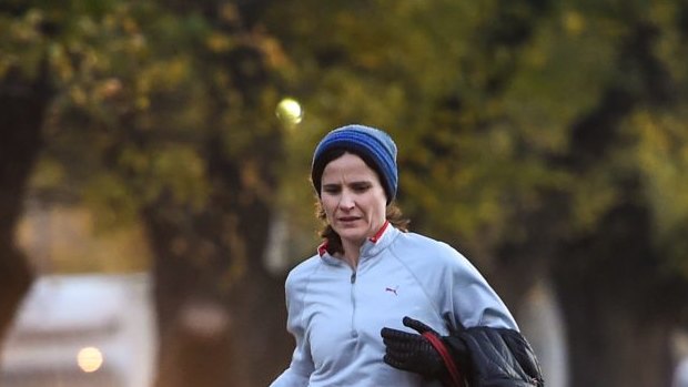 A jogger runs with her dog around Royal Park in the cold conditions this morning on the last day of autumn.