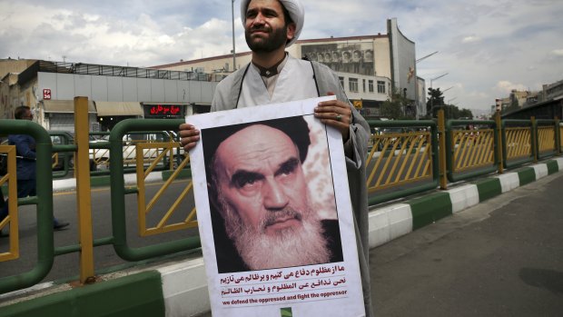 A cleric holds a poster showing portrait of the late Iranian revolutionary founder Ayatollah Khomeini at anti-American protests in Tehran on Friday.