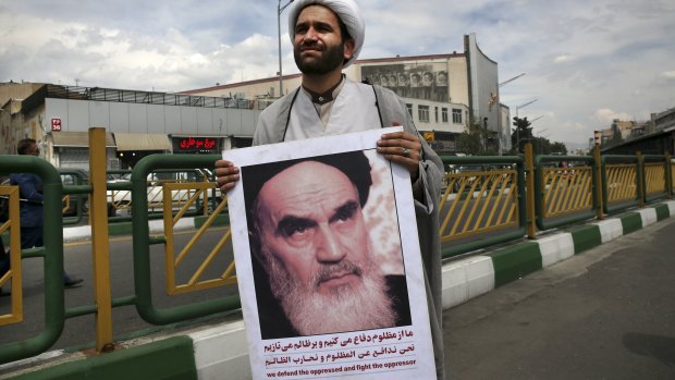 A cleric holds a poster showing portrait of the late Iranian revolutionary founder Ayatollah Khomeini at anti-American protests in Tehran on Friday.