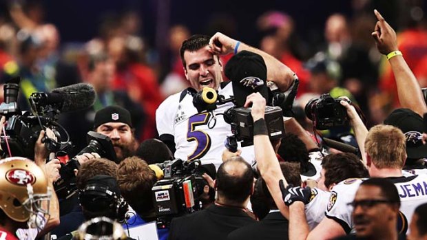 Star man ... Joe Flacco is lifted up by his teammates.