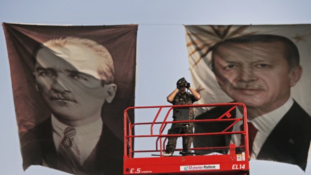A policeman between portraits of Turkish President Recep Tayyip Erdogan, right, and the republic's founder, Mustafa Kemal "Ataturk".
