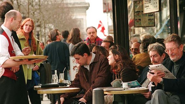 Parisians and tourists enjoy a drink at a cafe on the Champs Elysees avenue.