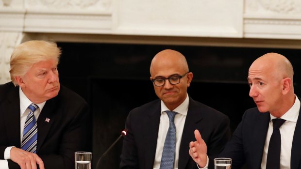 Not much love lost: Donald Trump (with Microsoft CEO Satya Nadella in the centre) listens to Amazon boss Jeff Bezos during an American Technology Council roundtable at the White House in June.