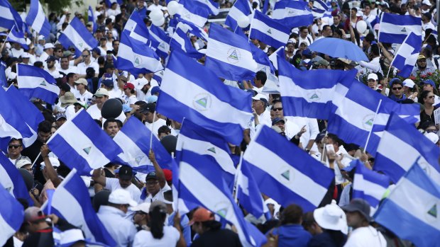 Demonstrators protesting government repression wave Nicaraguan flags in Managua.