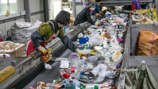 Workers separate plastic waste from other waste moving along a conveyor at a recycling facility in South Korea. In a bid to curb its own rampant pollution, China has clamped down on the import of unsorted paper and plastics. The effects of the strict new standards on halting impurities in waste imports are now being felt worldwide. 