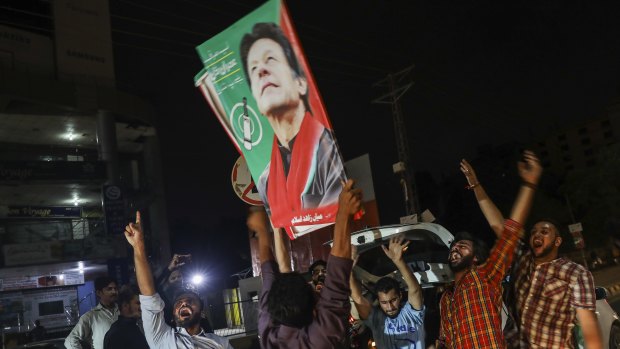 Supporters of Imran Khan hold signs while celebrating on a street in Lahore.
