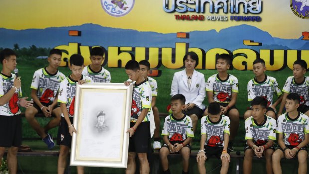 The soccer team shows their respect and thanks as they hold a portrait of Saman Gunan, the retired Thai SEAL diver who died during their rescue attempt.