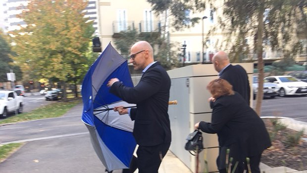 Ms Stojanovska's husband Dragi Stojanovski leaves court behind an umbrella flanked by his brother Vasko and mother Pisana. 