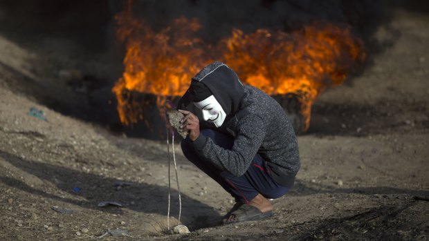 A Palestinian protester prepares a stone to hurl at Israeli troops during a protest at the Gaza Strip's border with Israel on Friday, as protests continued, albeit it with fewer people.