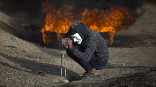 A Palestinian protester prepares a stone to hurl at Israeli troops during a protest at the Gaza Strip's border with Israel on Friday, as protests continued, albeit it with fewer people.