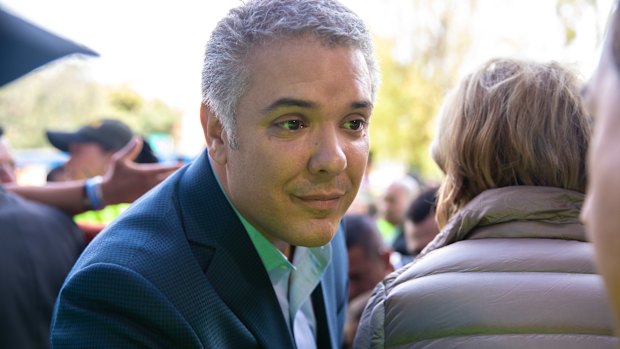 Ivan Duque listens as a voter speaks outside of a polling station.