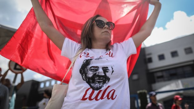 A supporter of former President Luiz Incio Lula da Silva holds a Worker\'s Party (PT) flag while waiting at the Federal Police headquarters in Curitiba, Brazil, on Saturday.
