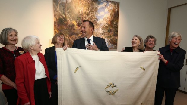 Prime Minister Tony Abbott meets with members of the ACT Embroiderers' Guild to view the baby blanket that will be given to Princess Charlotte, at Parliament House on Monday.