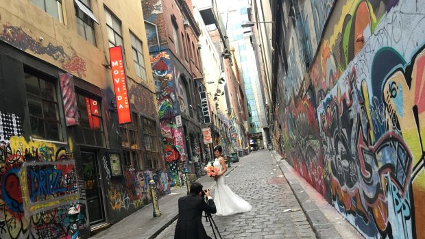 While Melbourne commutes to work a bride gets some wedding photographs taken in Hosier Lane.