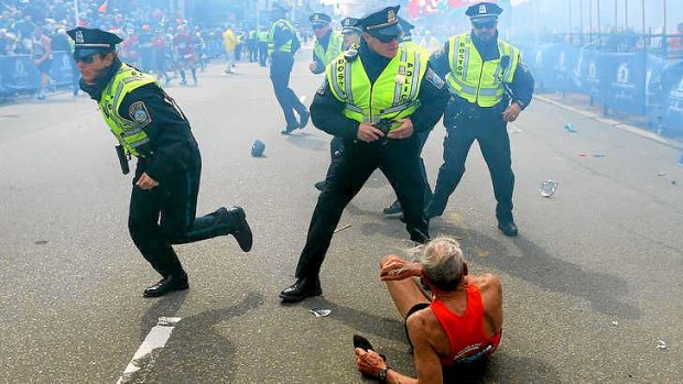 Bill Iffrig, 78, lies on the ground as police officers react to a second explosion at the finish line of the Boston Marathon.