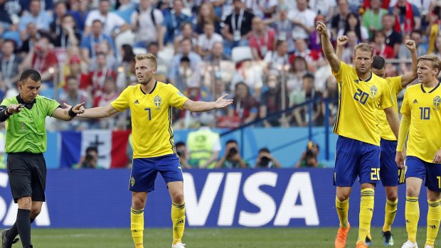 Sweden's Sebastian Larsson, second right, asks  referee Joel Aguilar to review a decision.