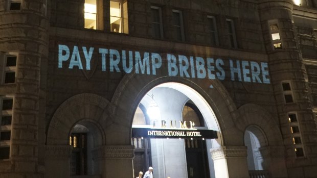 President Donald Trump’s Washington hotel is briefly illuminated with messages related to the emoluments clause.