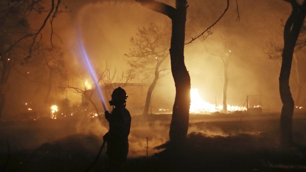 A firefighter sprays water on the fire in the town of Mati, east of Athens.