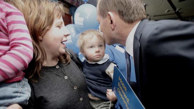 Opposition leader Tony Abbott kisses a young boy  at the Mernda Recreation Reserve in Victoria on Friday.