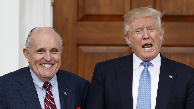 Then-President-elect Donald Trump calls out to media as he and former New York Mayor Rudy Giuliani pose for photographs in November 2016.