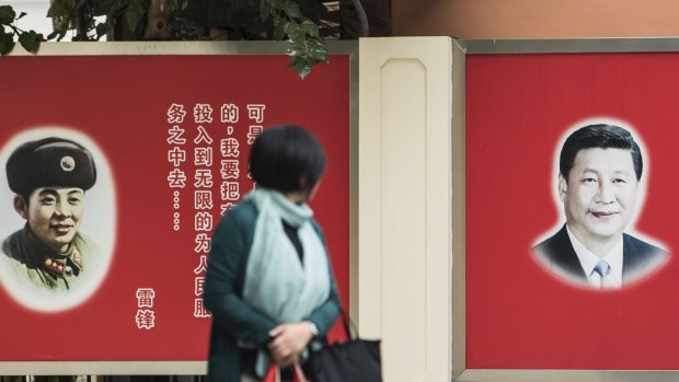 A woman looks towards posters featuring portraits of Xi Jinping, China's President, right, and Lei Feng, a former member of the People's Liberation Army in Shanghai, China.
