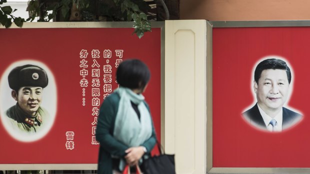 A woman looks towards posters featuring portraits of Xi Jinping, China's President, right, and Lei Feng, a former member of the People's Liberation Army in Shanghai, China.