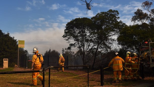 RFS crew members watch a helicopter move into position to drop water on the fire front.
