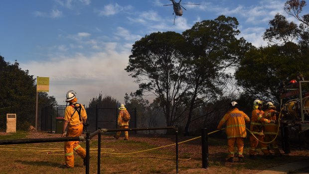 RFS crew members watch a helicopter move into position to drop water on the fire front.