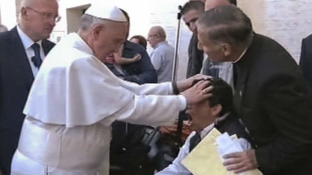 Pope Francis lays his hands on the head of a young man on Sunday, May 19, 2013, after celebrating Mass in St. Peter's Square. The young man heaved deeply a half-dozen times, convulsed and shook, and then slumped in his wheelchair as Francis prayed over him. T