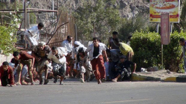 Yemenis run from gunfire at an army base in Aden.