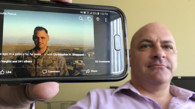 Marine Corps veteran Chris Sheppard poses with a picture of himself taken during his service in Iraq in October 2004, at his office in Seattle.