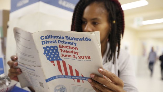 Nurse Nikko Johnson reviews the California Primary election guide at San Francisco City Hall.