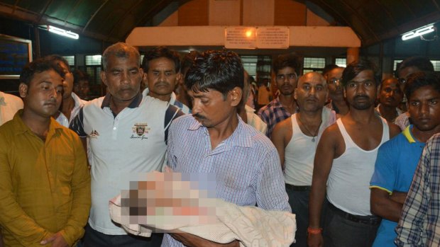 A man holds the lifeless body of his child outside Baba Raghav Das Medical College Hospital in Gorakhpur.